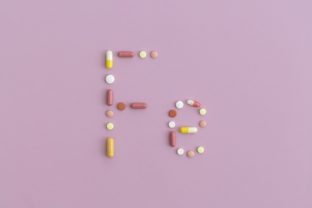 Iron symbol made from pills on purple background. Top view with copy space. Flat lay.